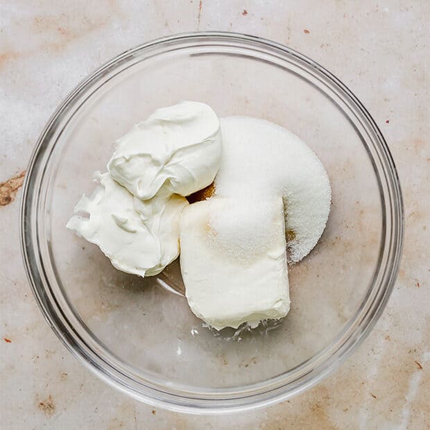 Cream cheese, sour cream, sugar, and vanilla extract in a bowl.