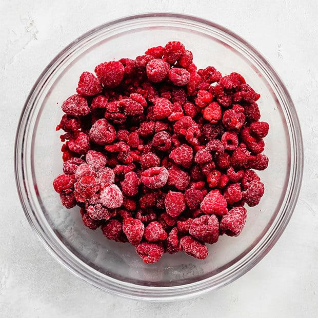 A bowl full of frozen raspberries.