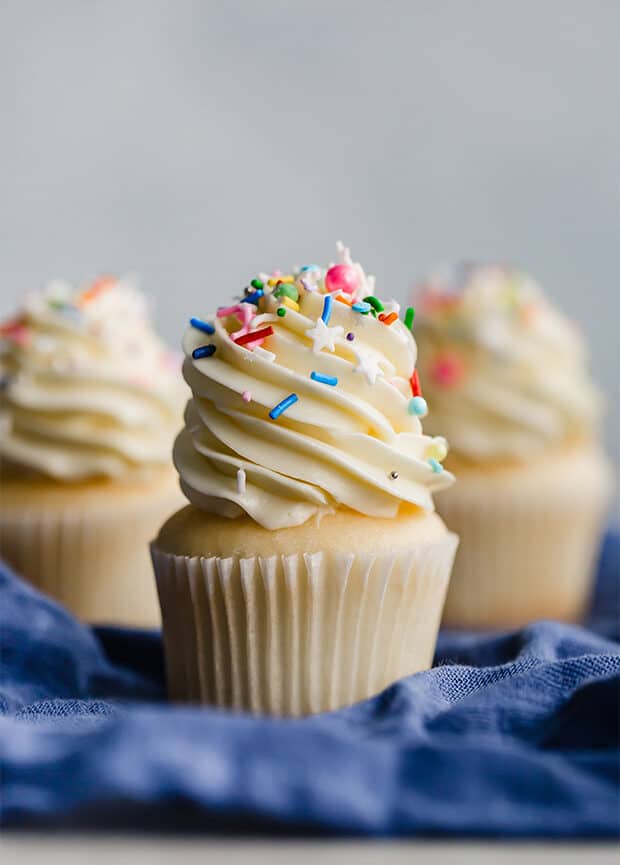 A vanilla cupcake topped with Swiss meringue buttercream and colorful sprinkles.