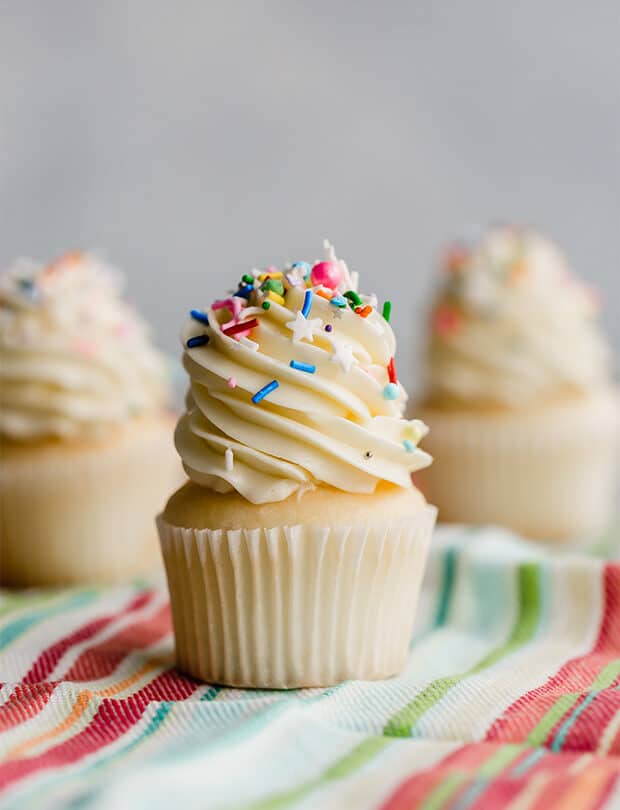 A cupcake topped with Swiss meringue buttercream and colorful sprinkles.