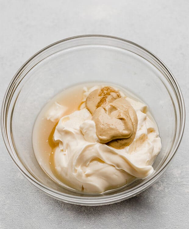 A glass bowl with mayo, vinegar, and dijon mustard in it.