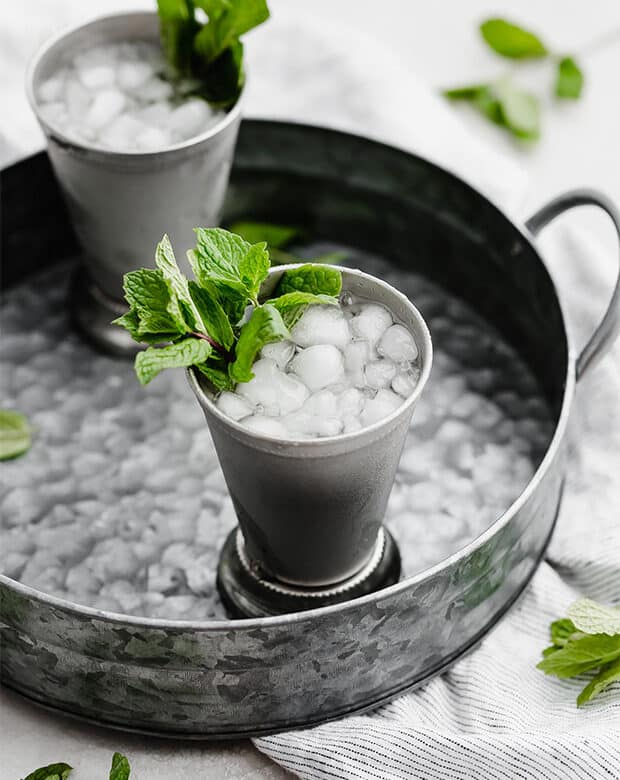 A virgin mint julep in a metal cup on a silver metal tray.