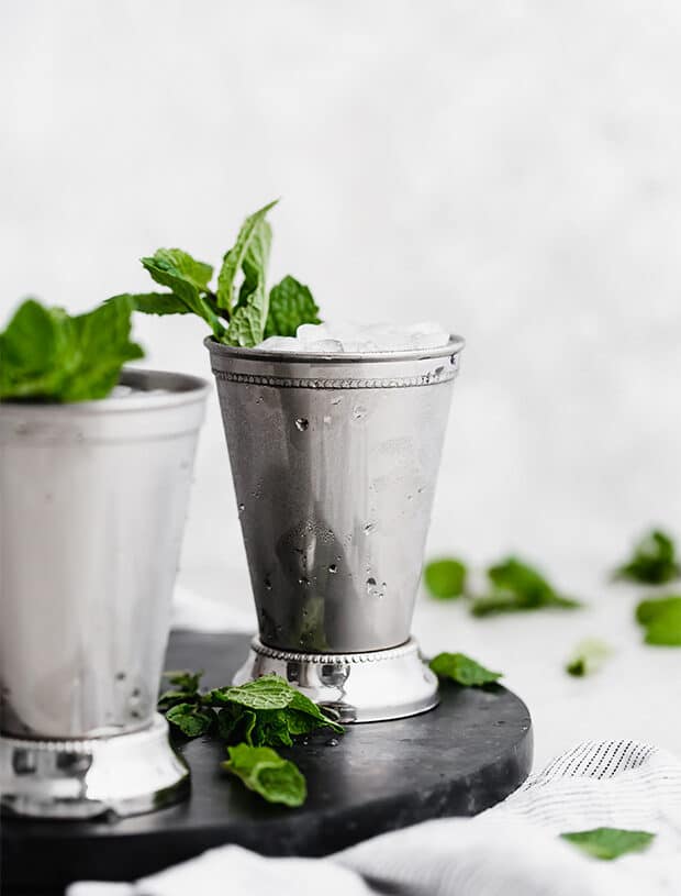 A straight on photo of a mint julep in a silver cup.