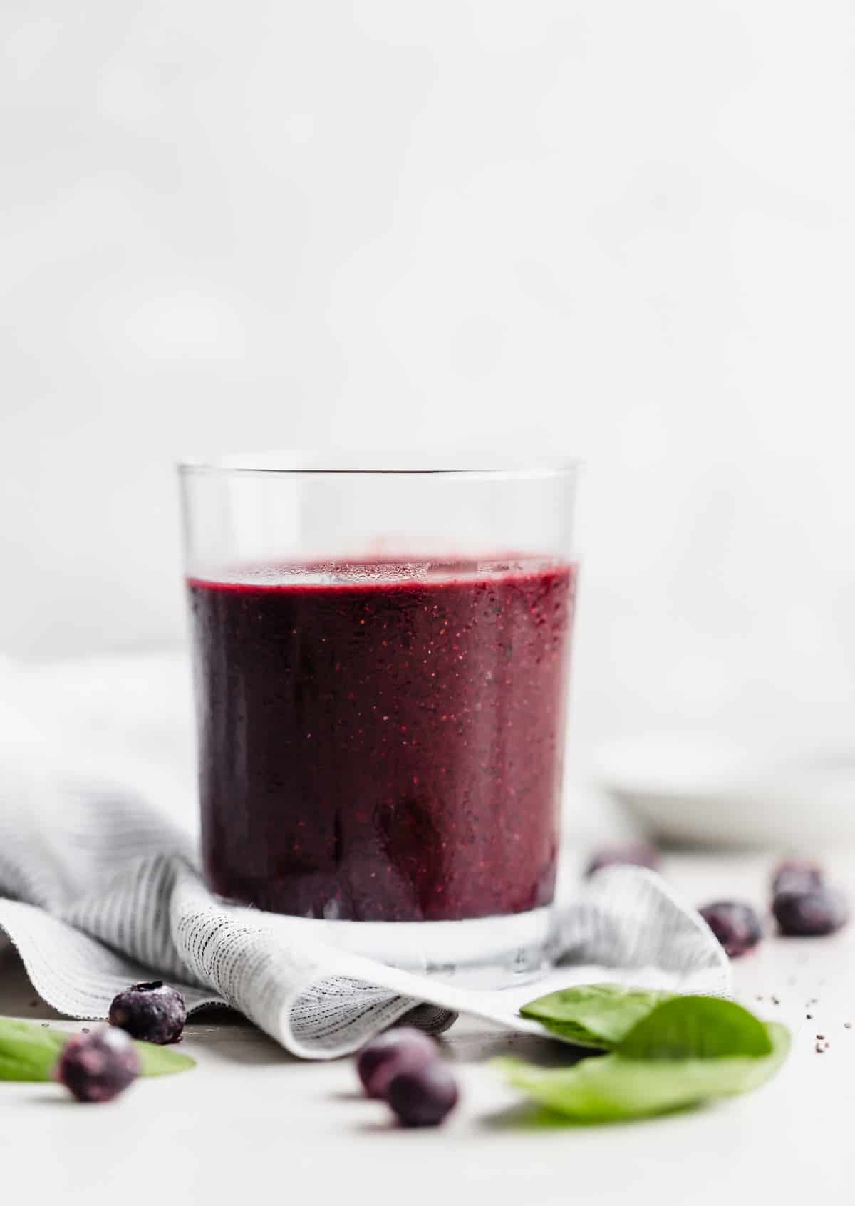 Dark purple Acai Smoothie in a clear glass against a white background.