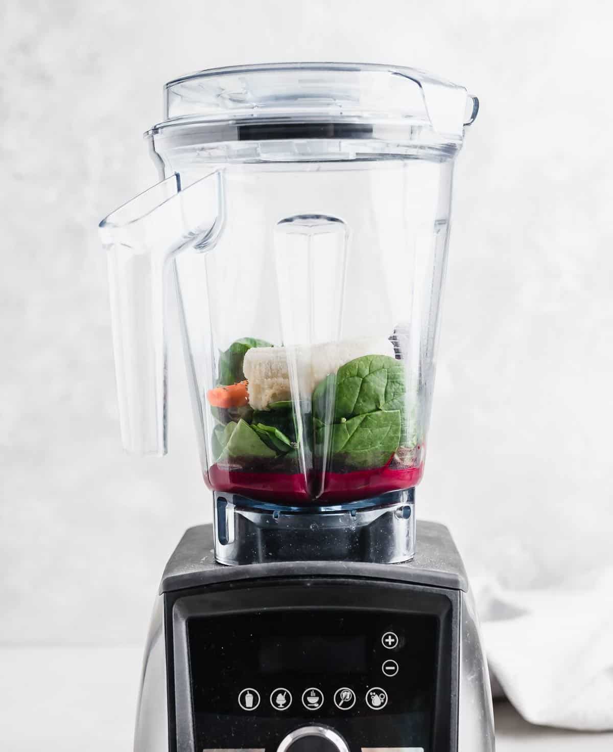 A blender filled with healthy Acai Smoothie ingredients against a white background. 