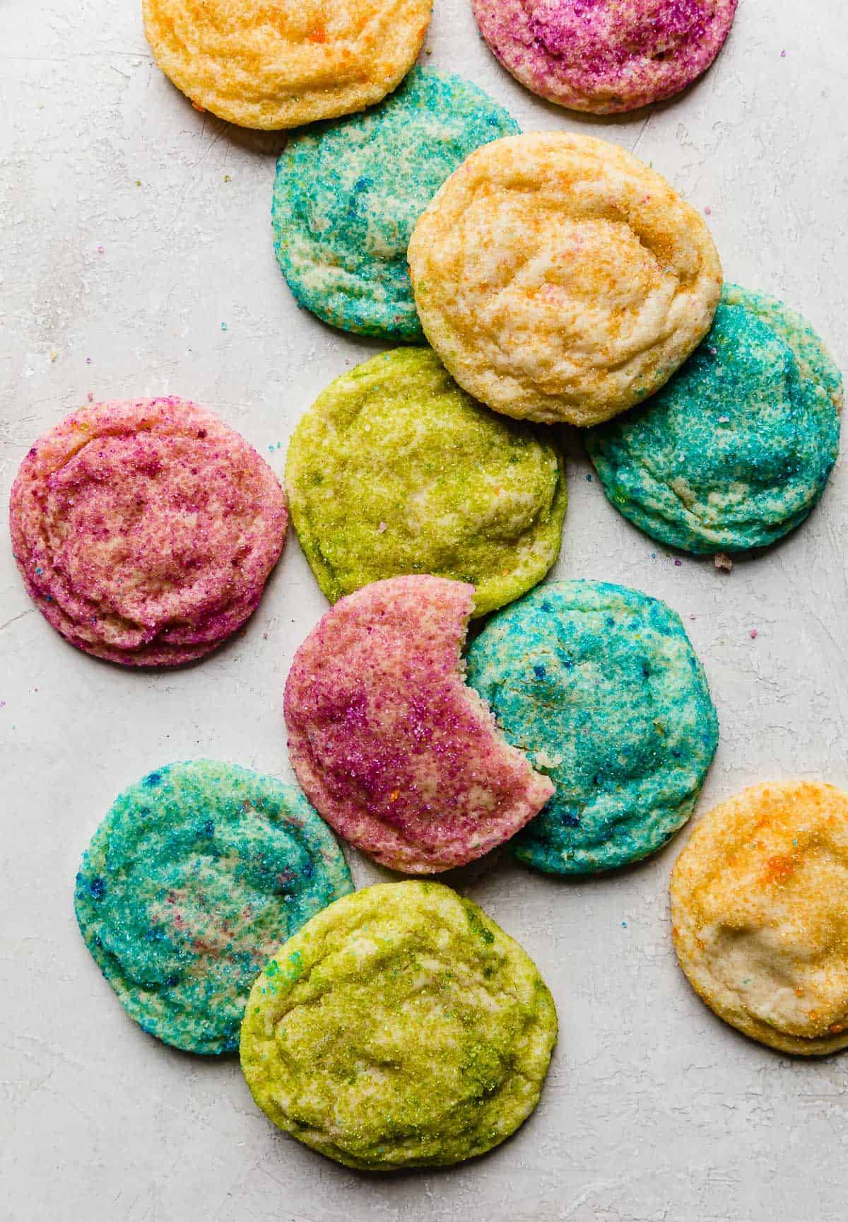 Purple, blue, yellow, and green sugar coated cookies on a white background.