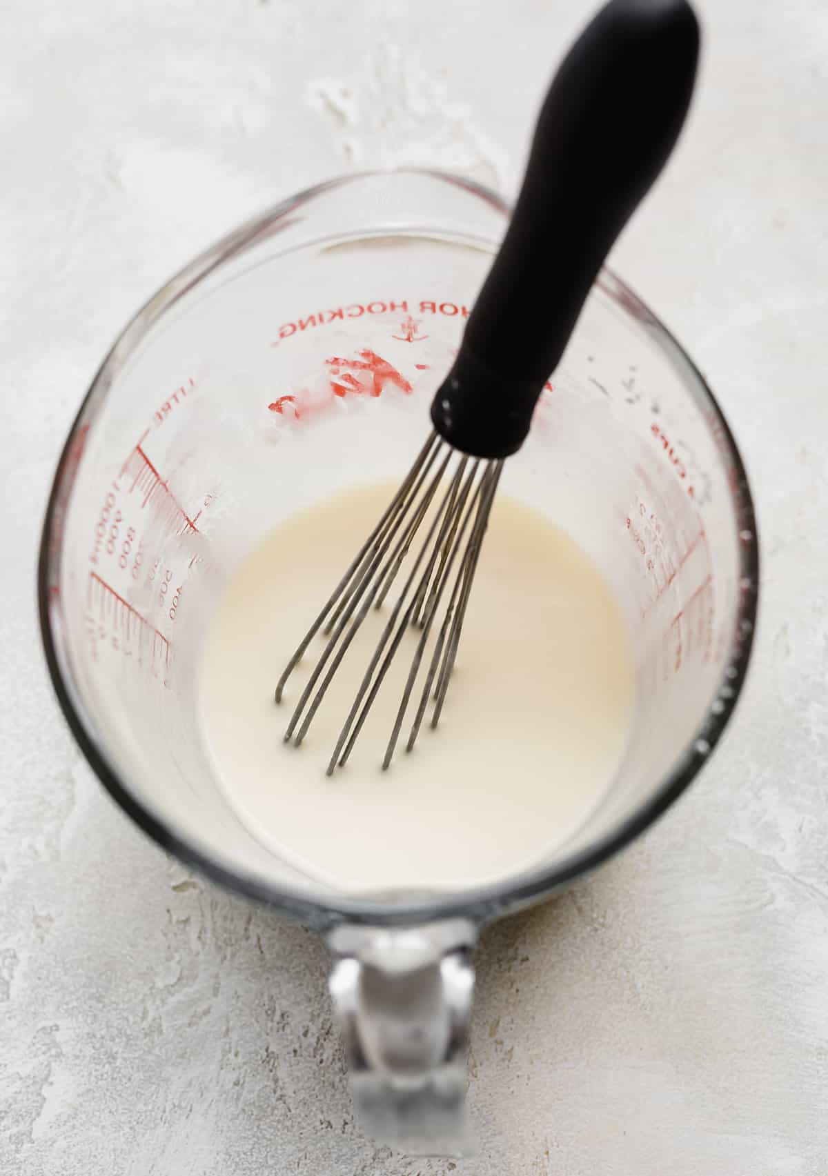 White glaze mixture in a liquid measuring cup.