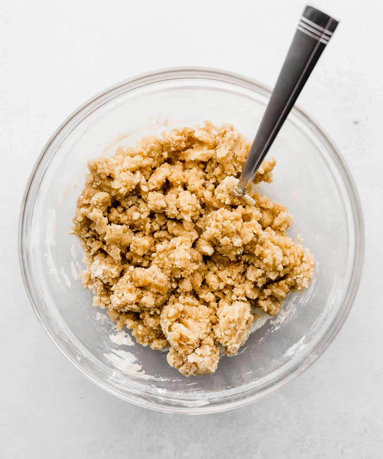 A crumbly crumb topping in a glass bowl on a white background.
