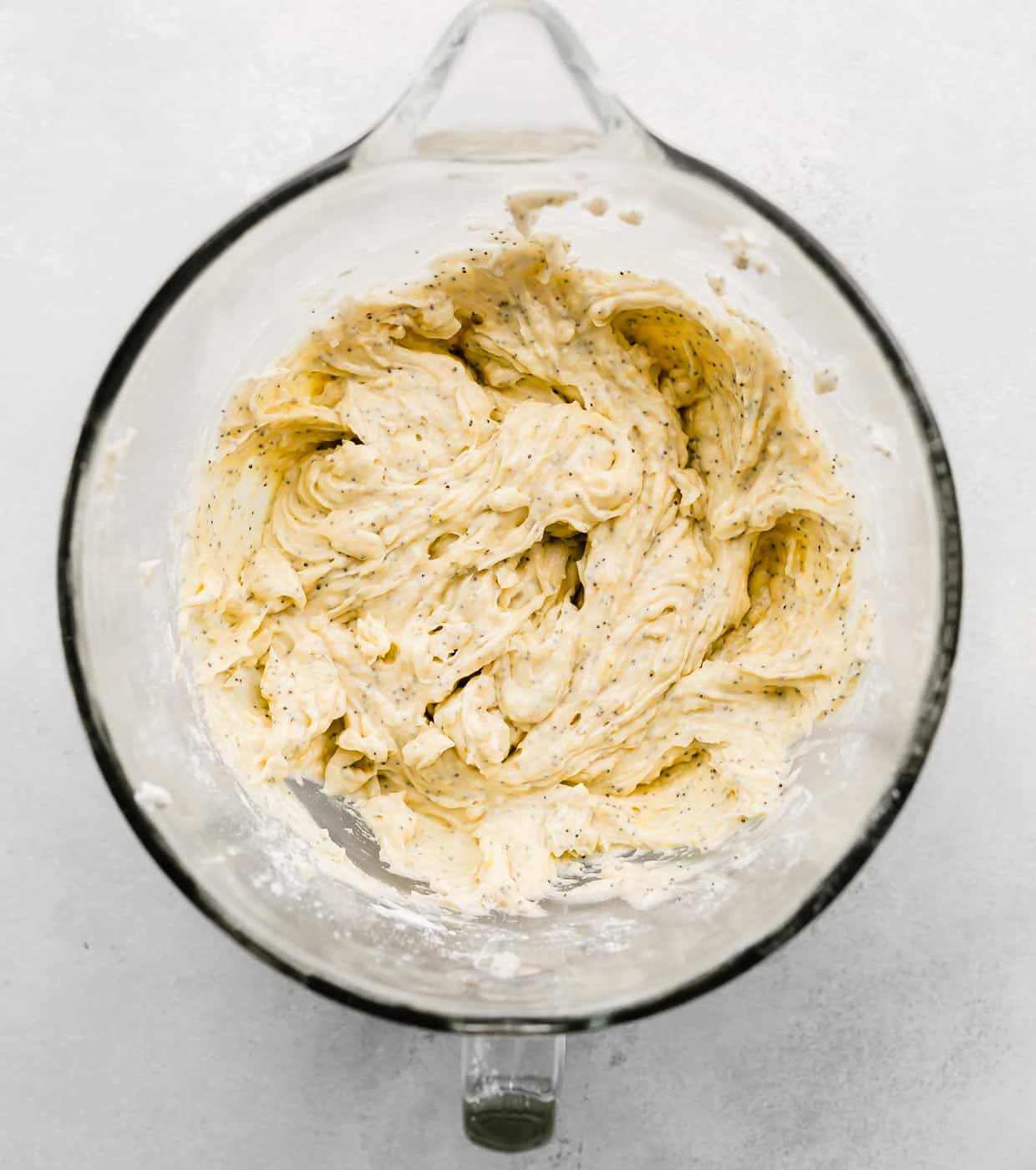 Lemon Poppy Seed Muffin batter in a glass mixing bowl on a white background.