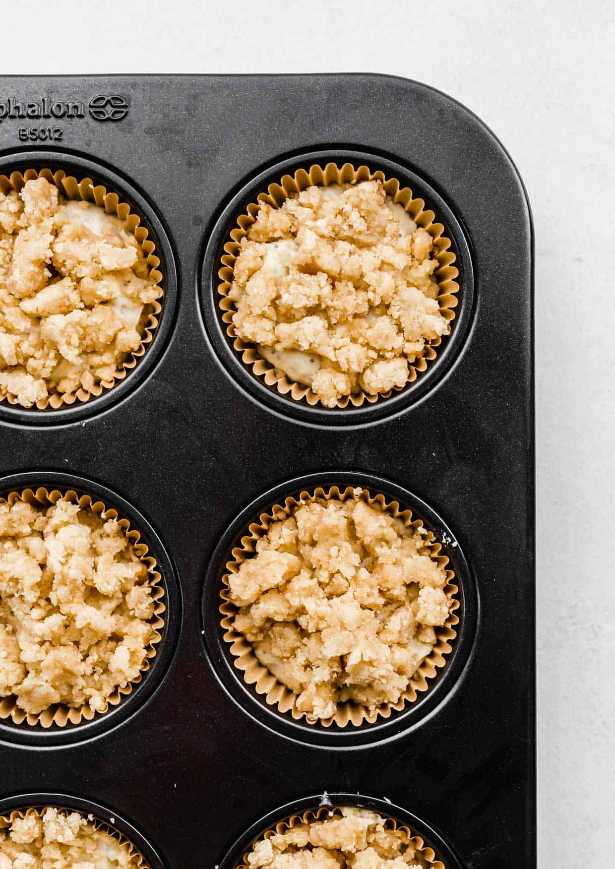 Crumb topping over Lemon Poppy Seed Muffin batter in a muffin tin.