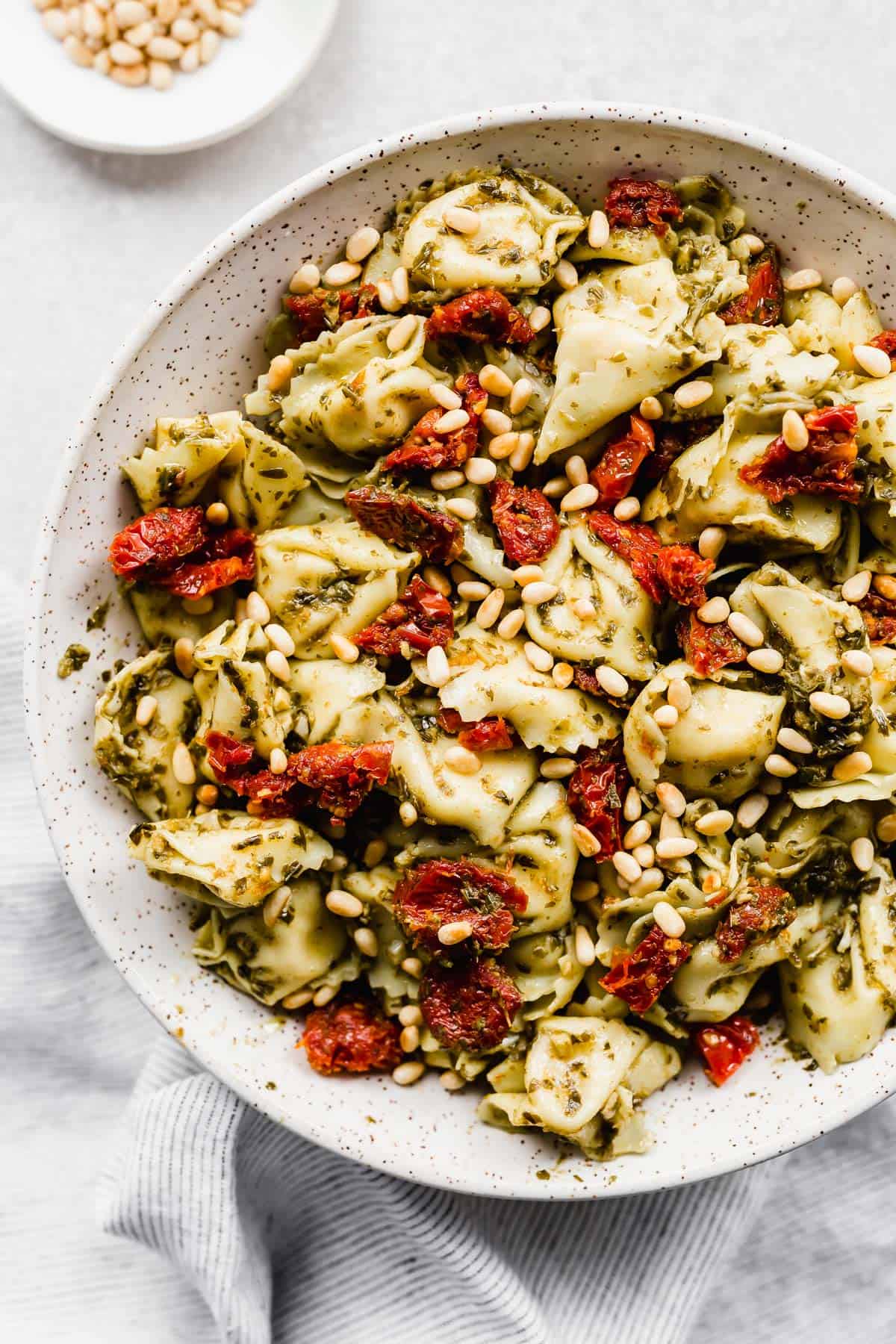 Pesto Tortellini Pasta Salad with sun-dried tomatoes and pine nuts.