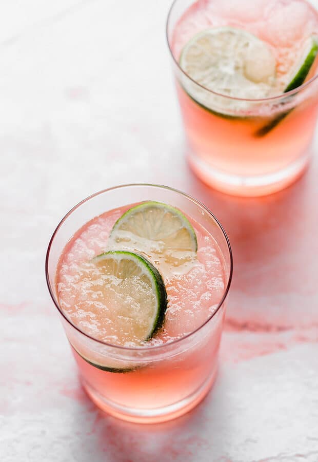 Two glasses of Limeade Slush Punch with lime slices in each glass. 