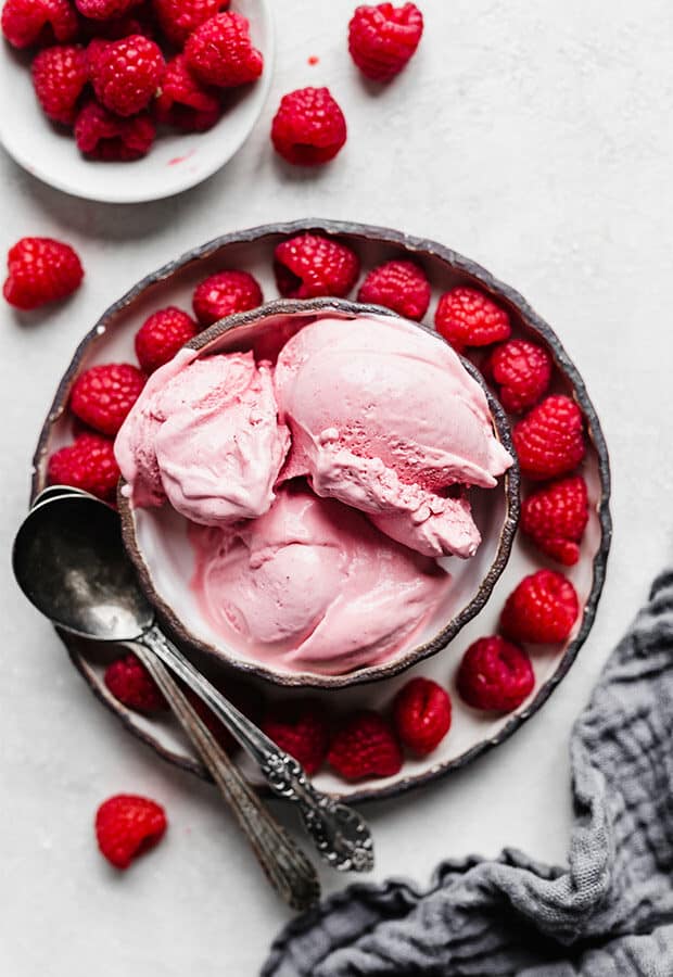Overhead photo of Raspberry Ice Cream in a bowl surrounded by fresh raspberries.