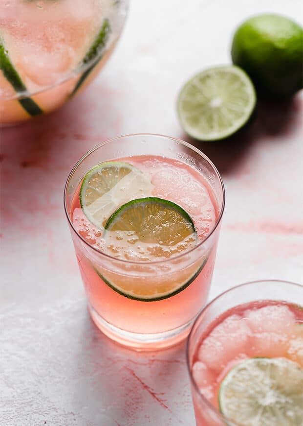 A glass of Limeade Slush Punch with 2 lime slices in the cup.