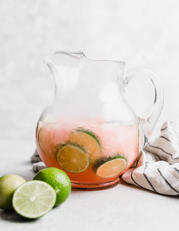 A pitcher full of Limeade Slush Punch and lime slices.
