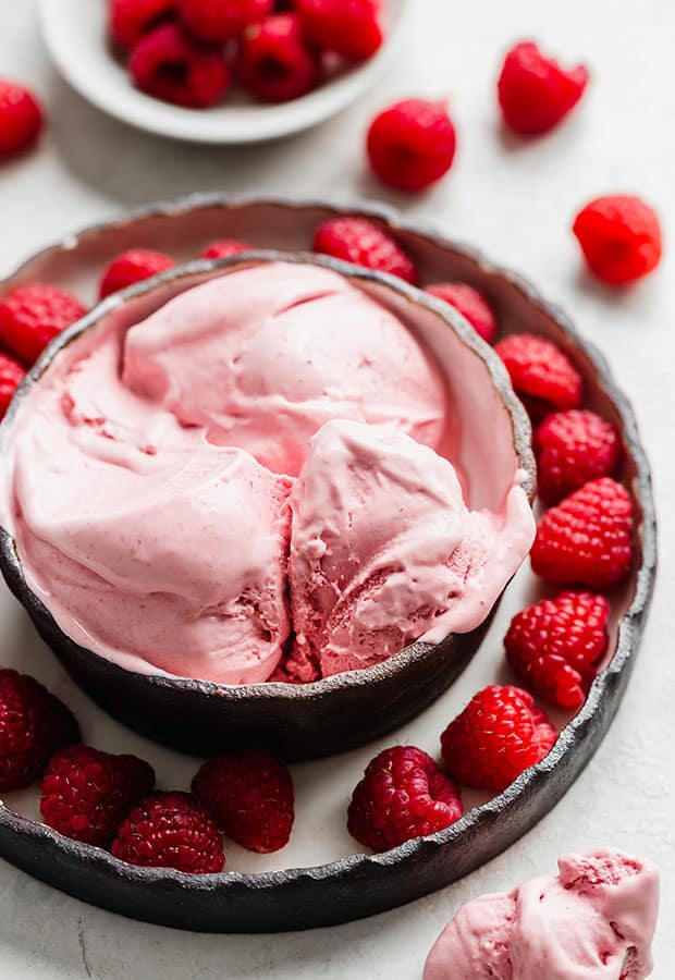 A bowl of Raspberry Ice Cream with fresh raspberries surrounding it.