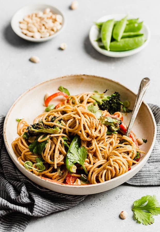 A plate of Peanut Noodles with veggies against a white background.