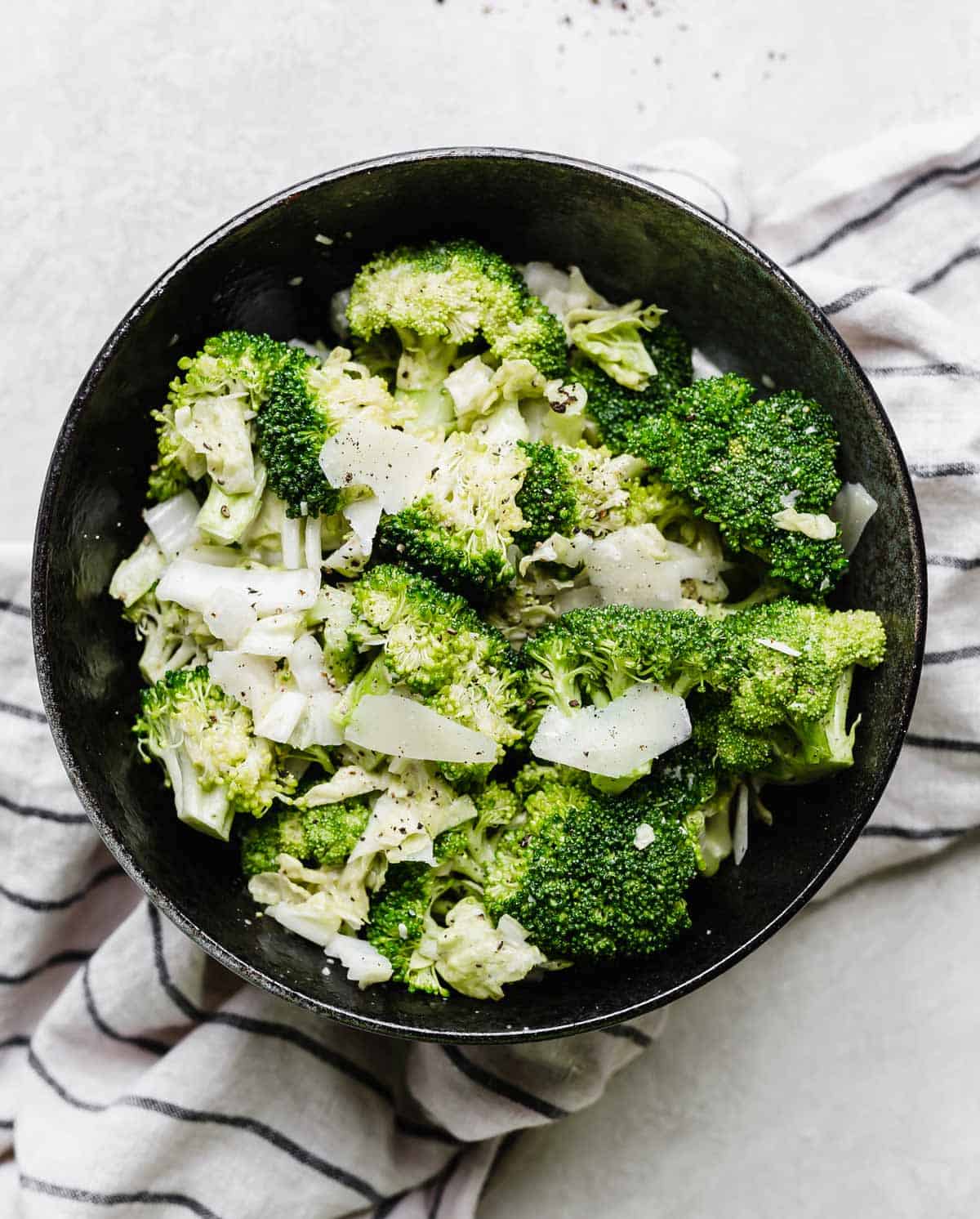 Broccoli Caesar Salad with cabbage in a black bowl on a light gray background.
