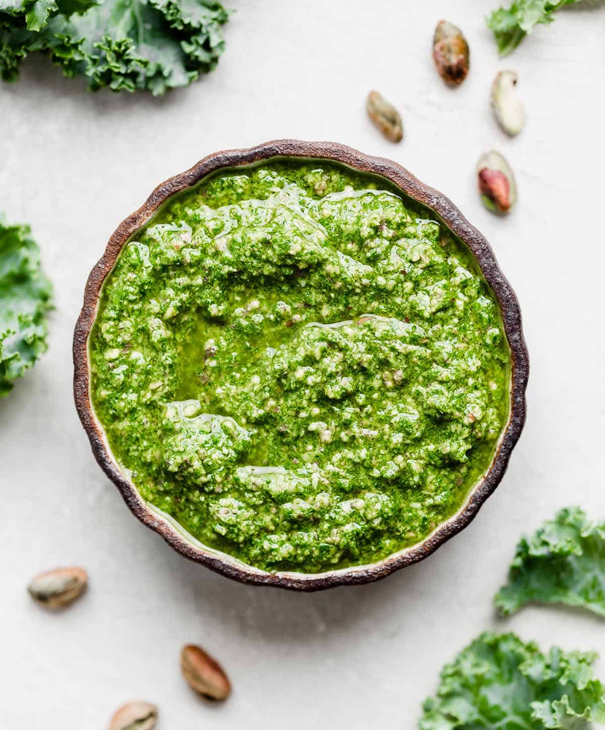 A black bowl filled with bright green kale pesto.