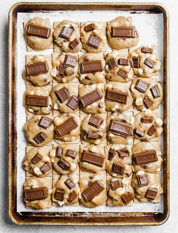 A baking sheet lined with cookie dough topped graham cracker squares.