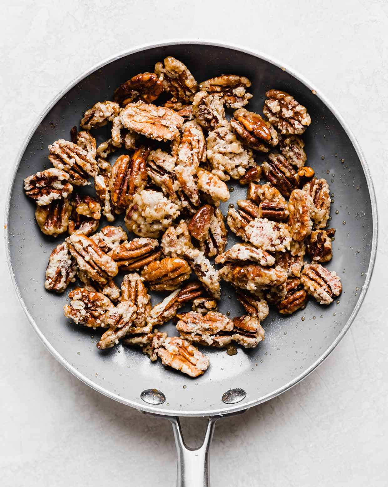 Sugared pecans in a gray skillet.