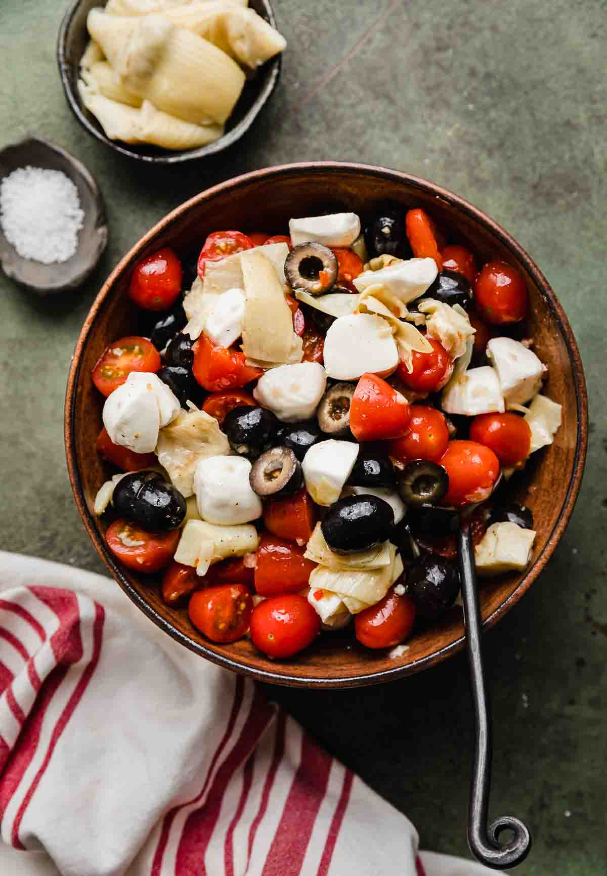 A brown bowl with Tomato Artichoke Salad in it.