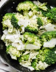 A pepper sprinkled Broccoli Caesar Salad in a black bowl.