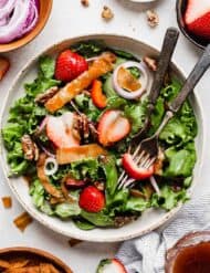 A fresh Strawberry Spinach Salad recipe topped with a homemade strawberry dressing, red onion, candied pecans, fried wontons.