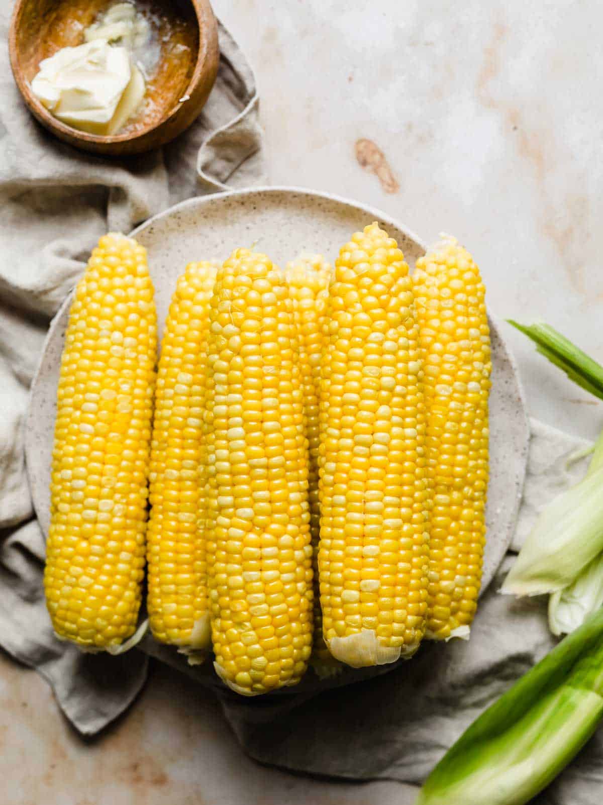 How to boil corn perfectly, showing six cooked corns on a plate.