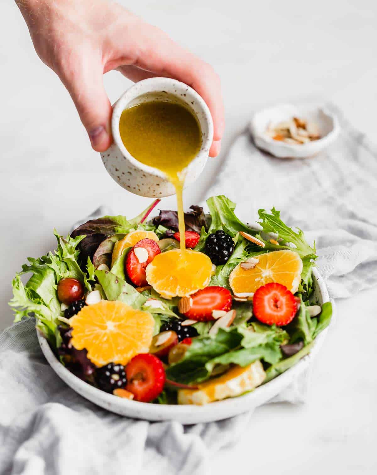 Citrus vinaigrette being poured over a citrus salad.