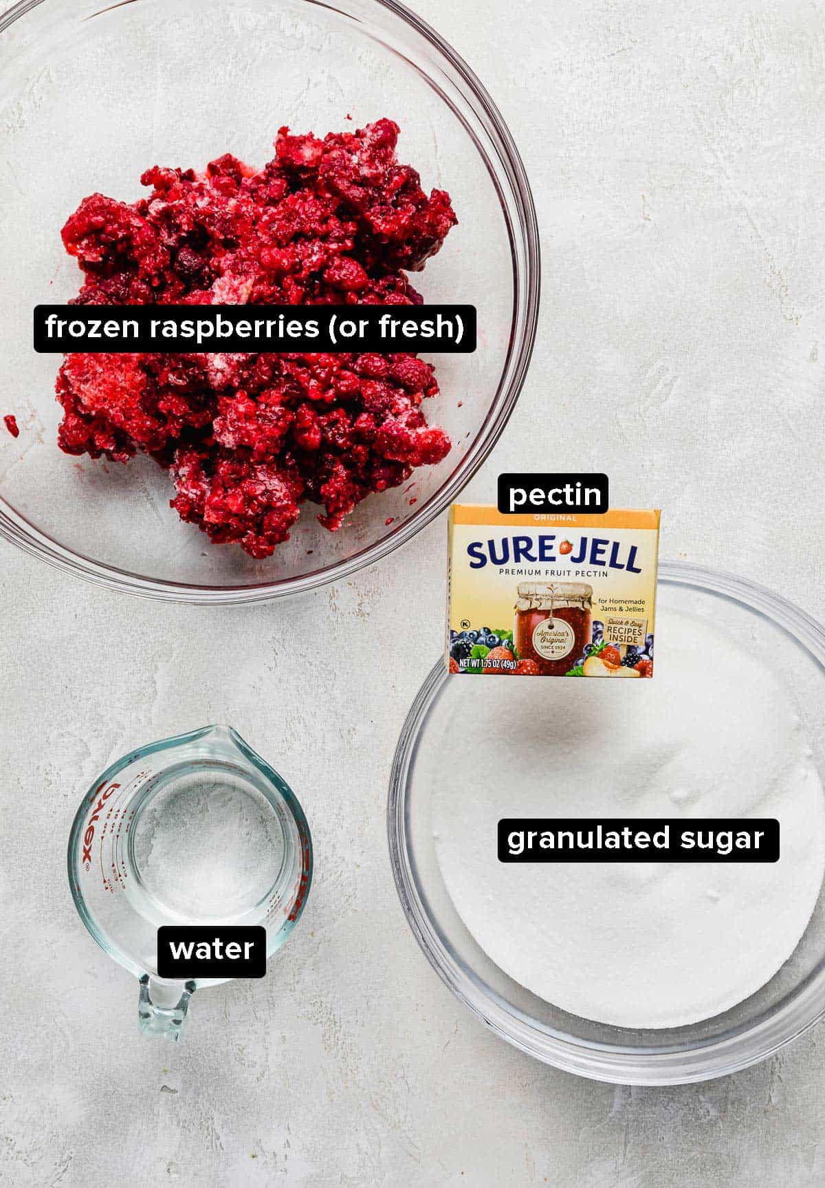 Raspberry Freezer Jam ingredients on a white textured background.