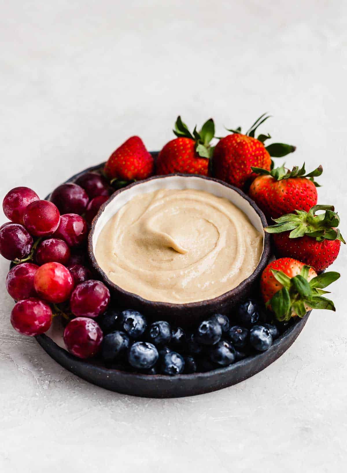 Three ingredient cream cheese fruit dip in a bowl on a light gray background.