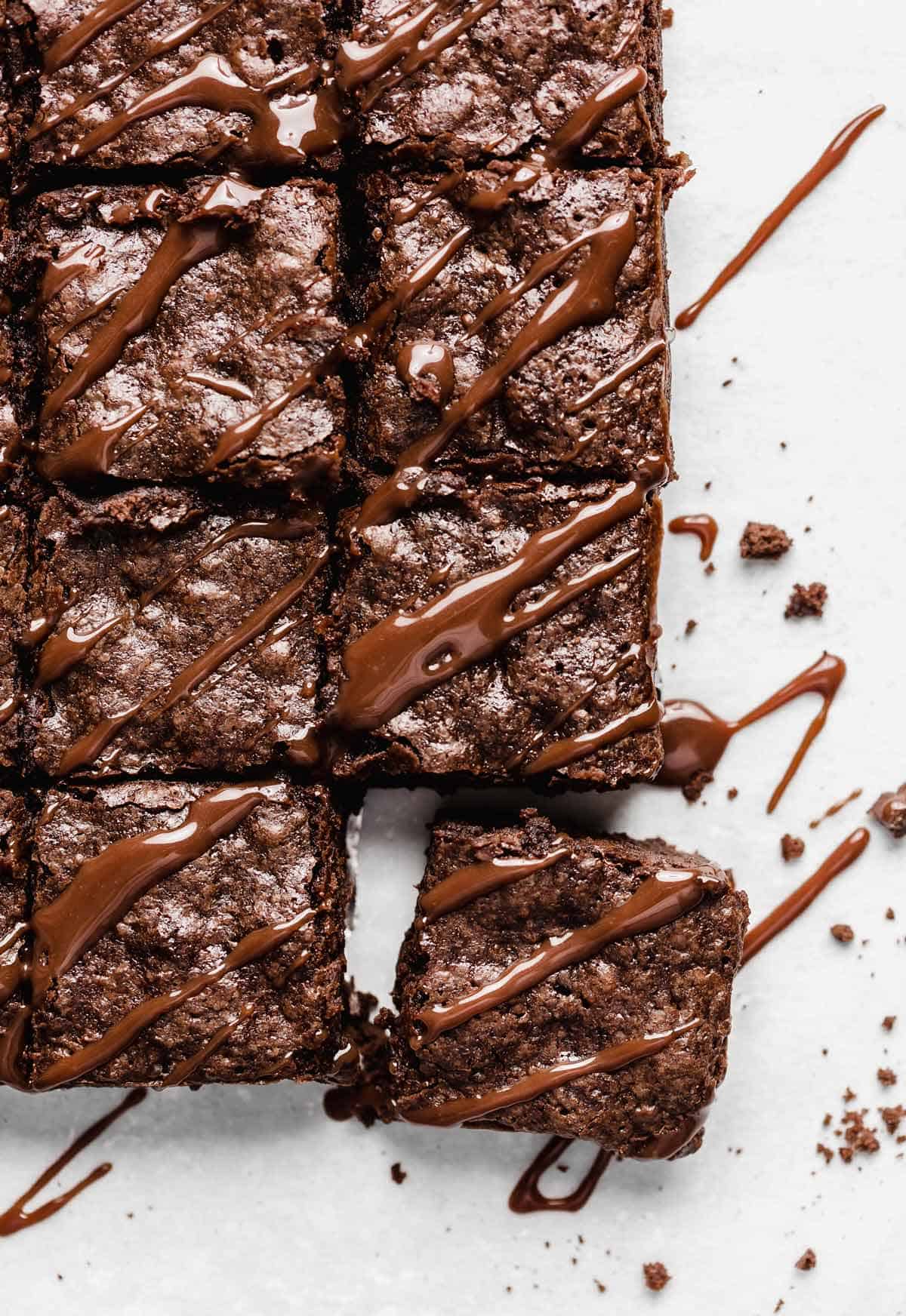 Homemade Brownies cut into small squares with hot fudge drizzled overtop.