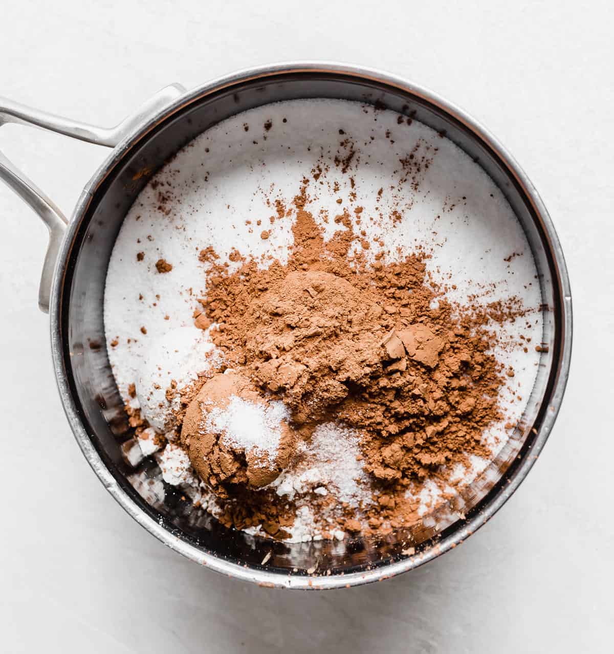 A saucepan with sugar, flour, cocoa powder and salt in it.