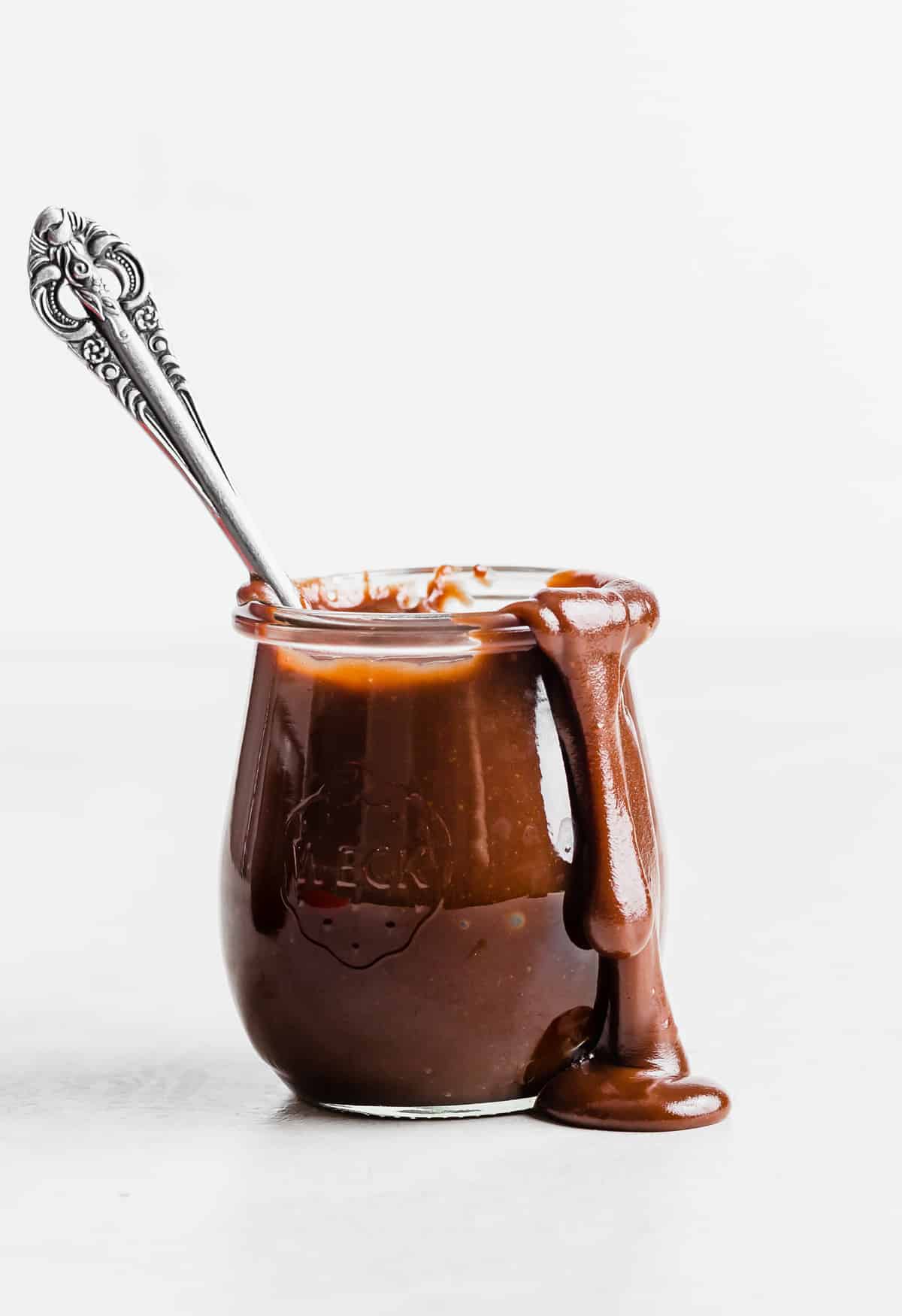 Hot Fudge Sauce made with evaporated milk in a glass jar against a white background.