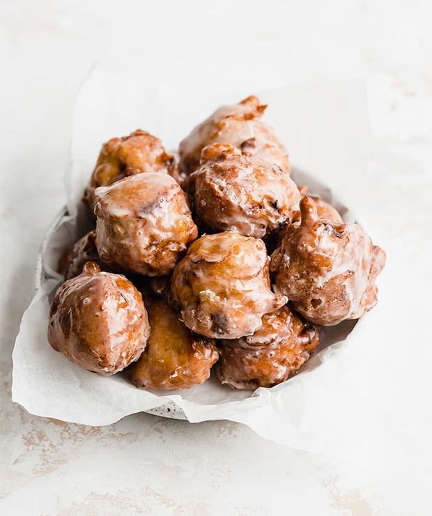 A plate full of homemade peach fritters on a white background.