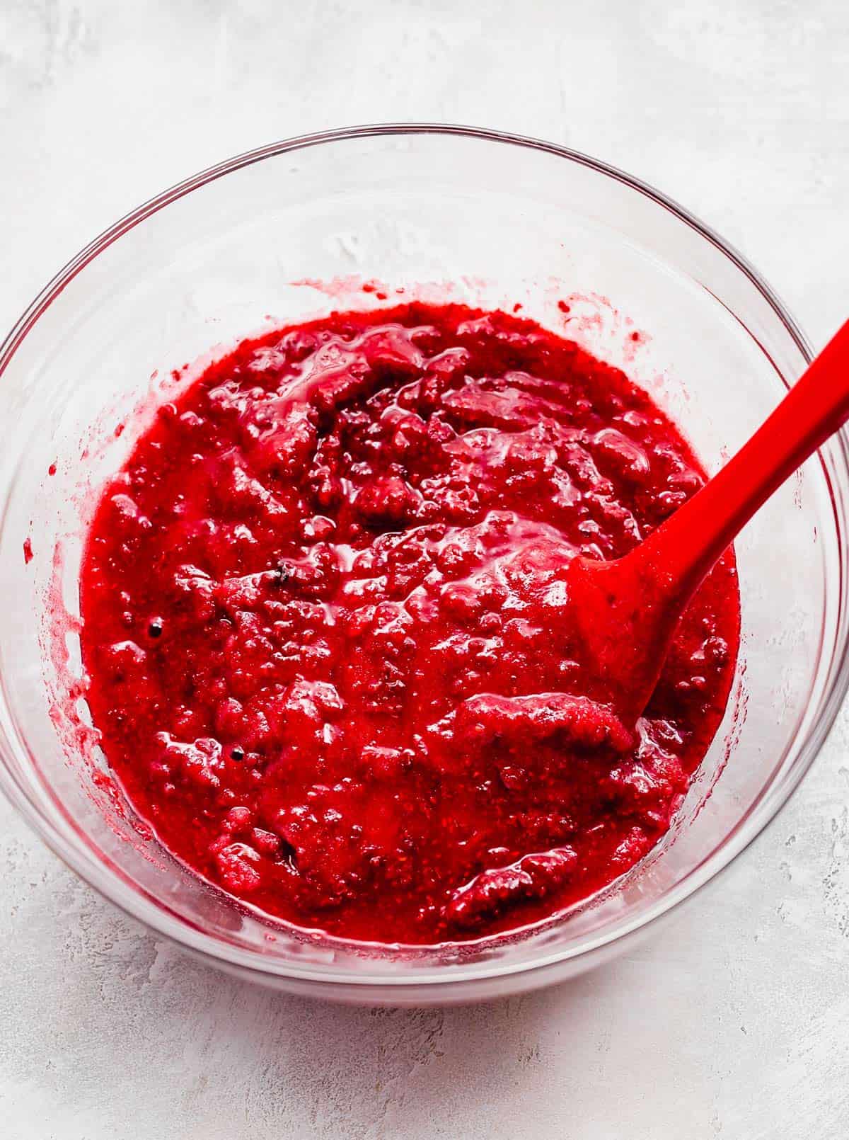 A red raspberry sauce in a glass bowl.