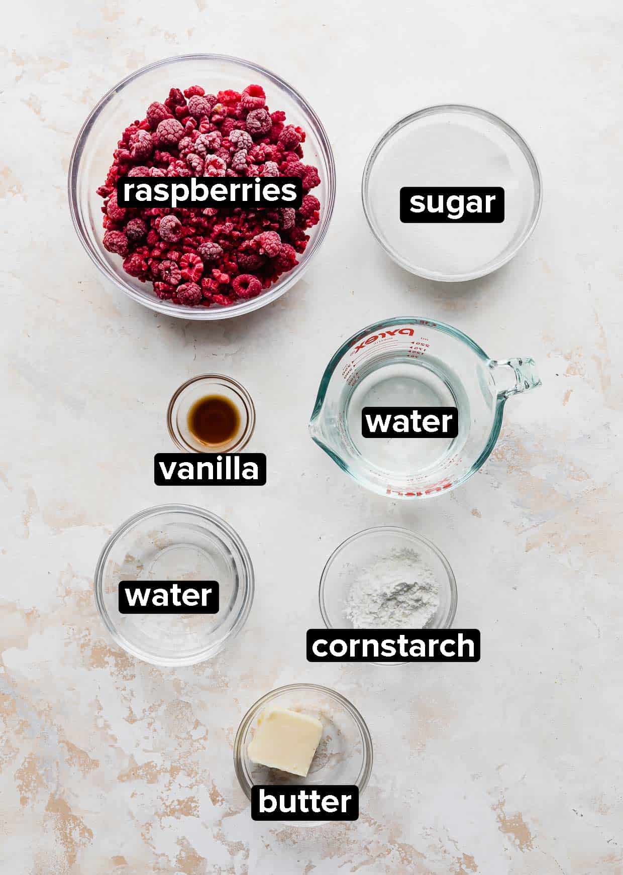 Ingredients used to make raspberry sauce on a cream textured background. 