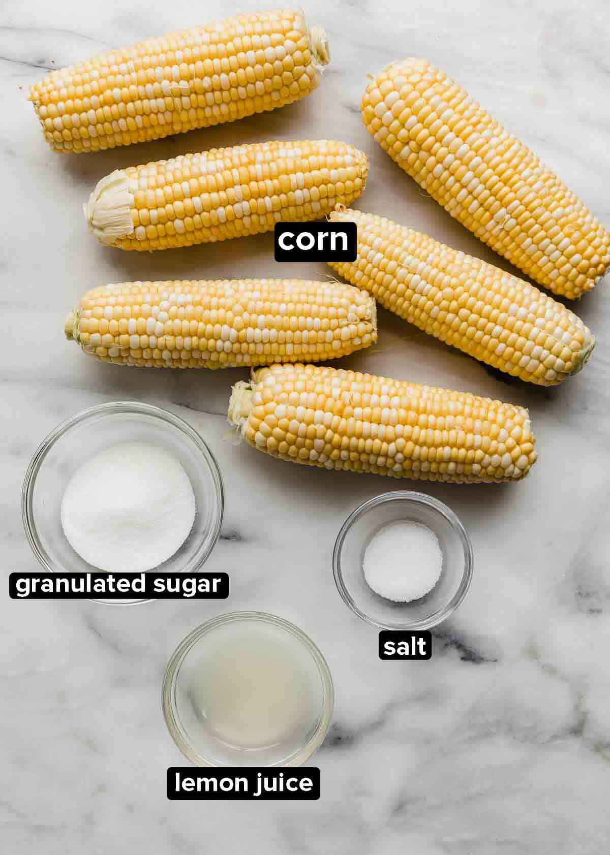 Ingredients used to make sweet boiled corn (or how to boil corn): husked raw corn on the cob, sugar, lemon juice, and salt.