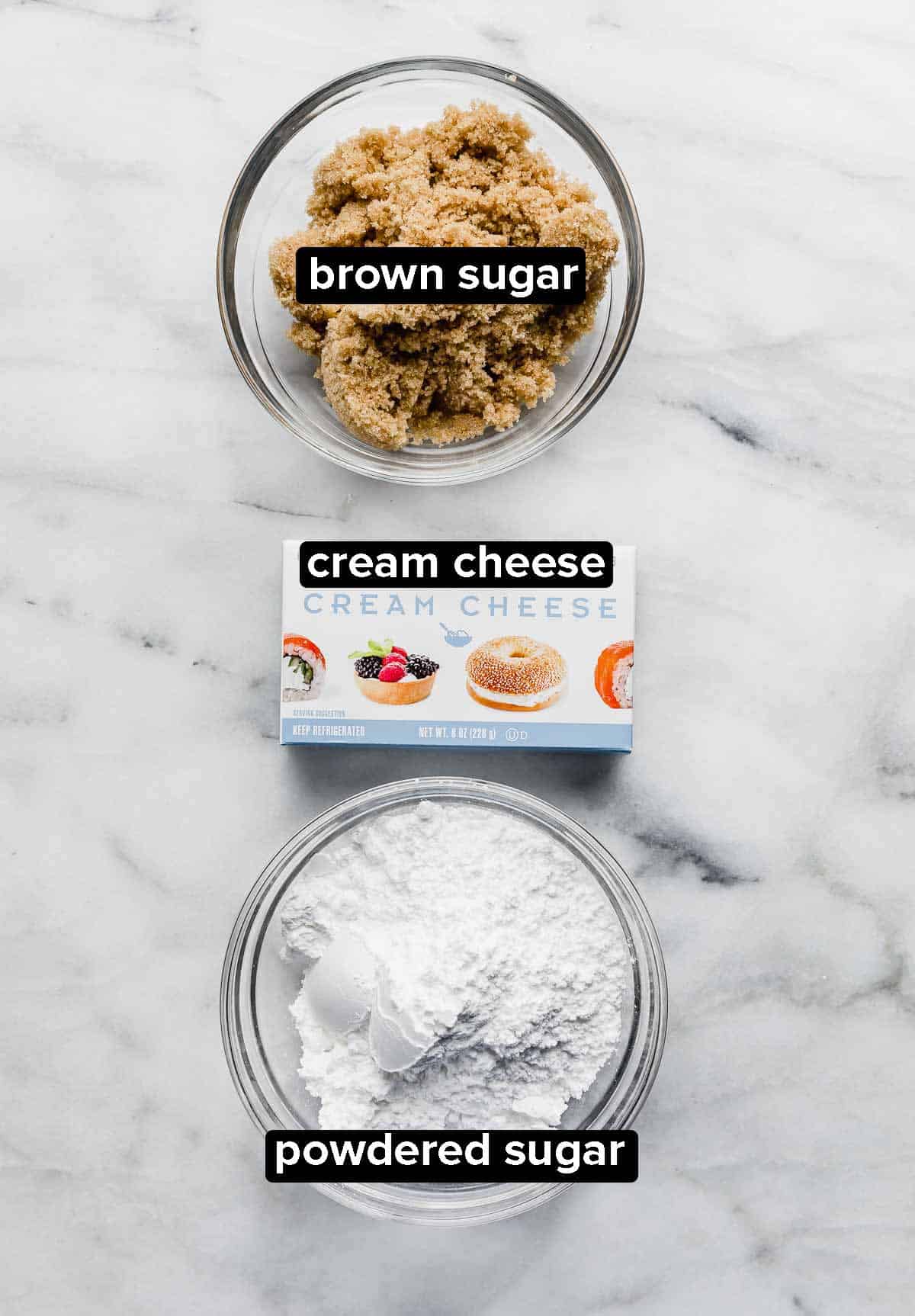 Three ingredients to make Cream Cheese Fruit Dip on a white background: brown sugar, cream cheese, and powdered sugar.