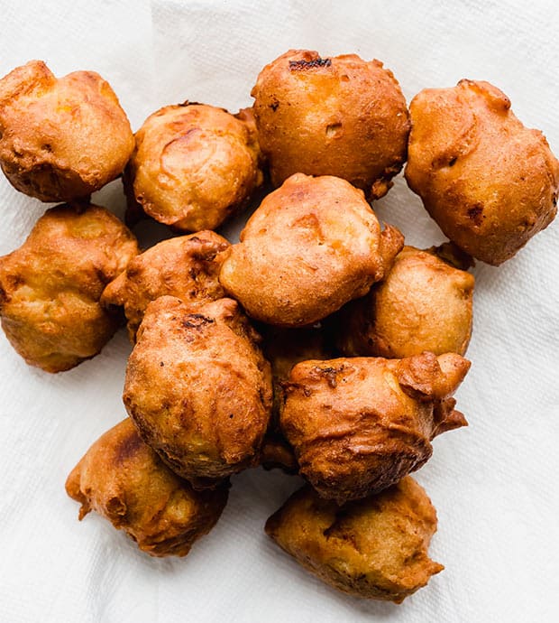 A plate of deep golden brown fried peach fritters.