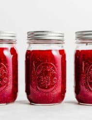 Three jars of Raspberry Freezer Jam against a white background.