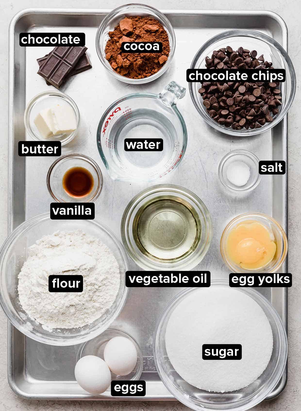 Homemade brownie ingredients portioned into glass bowls on a silver baking tray.