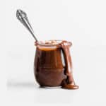 A jar of old fashioned hot fudge sauce with a spoon in the jar.