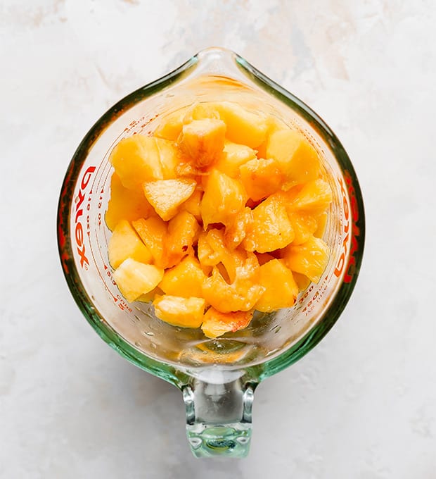 Chopped peaches in a glass measuring cup.