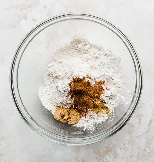A bowl with dry ingredients in it: flour, brown sugar, cinnamon, and nutmeg.