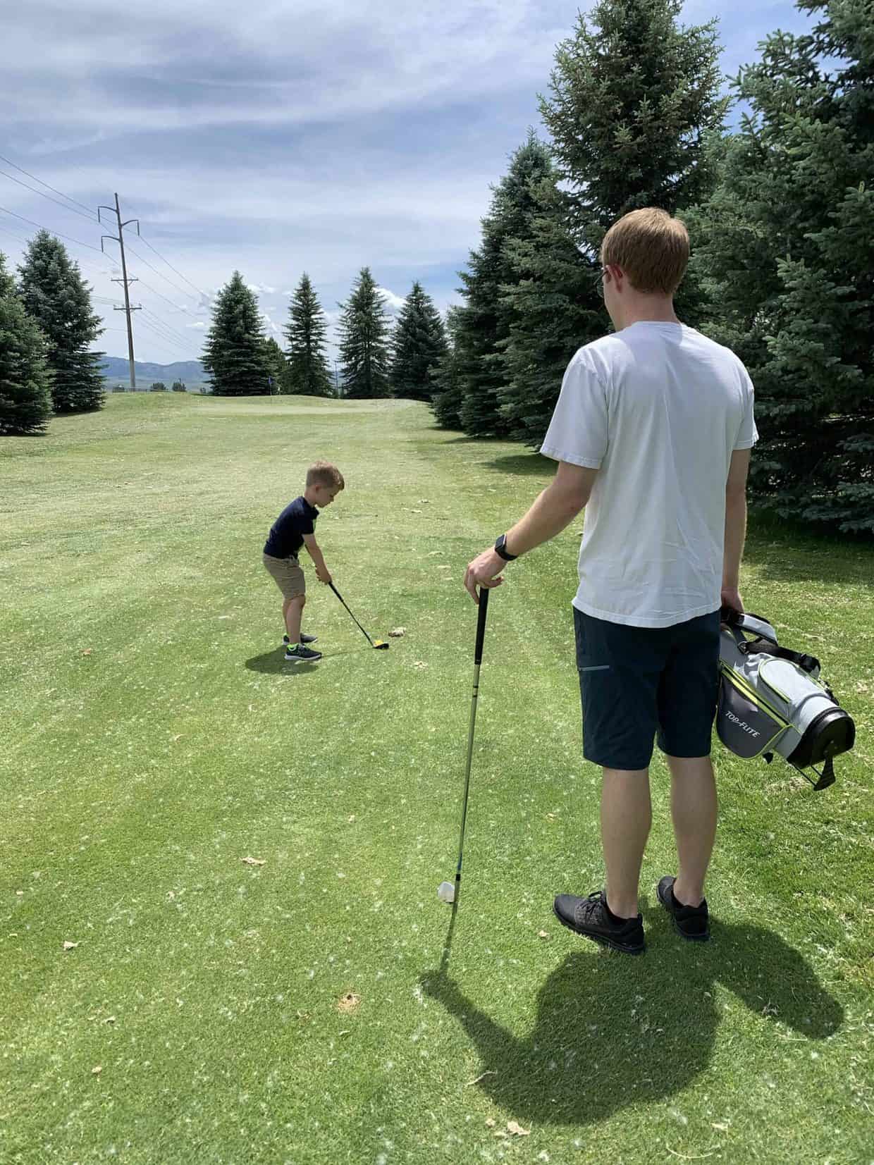 A young boy golfing.