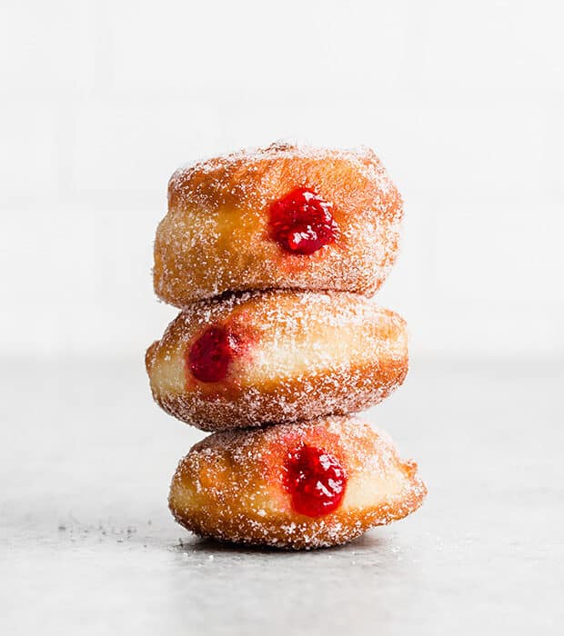 A stack of 3 donuts filled with raspberry jam.