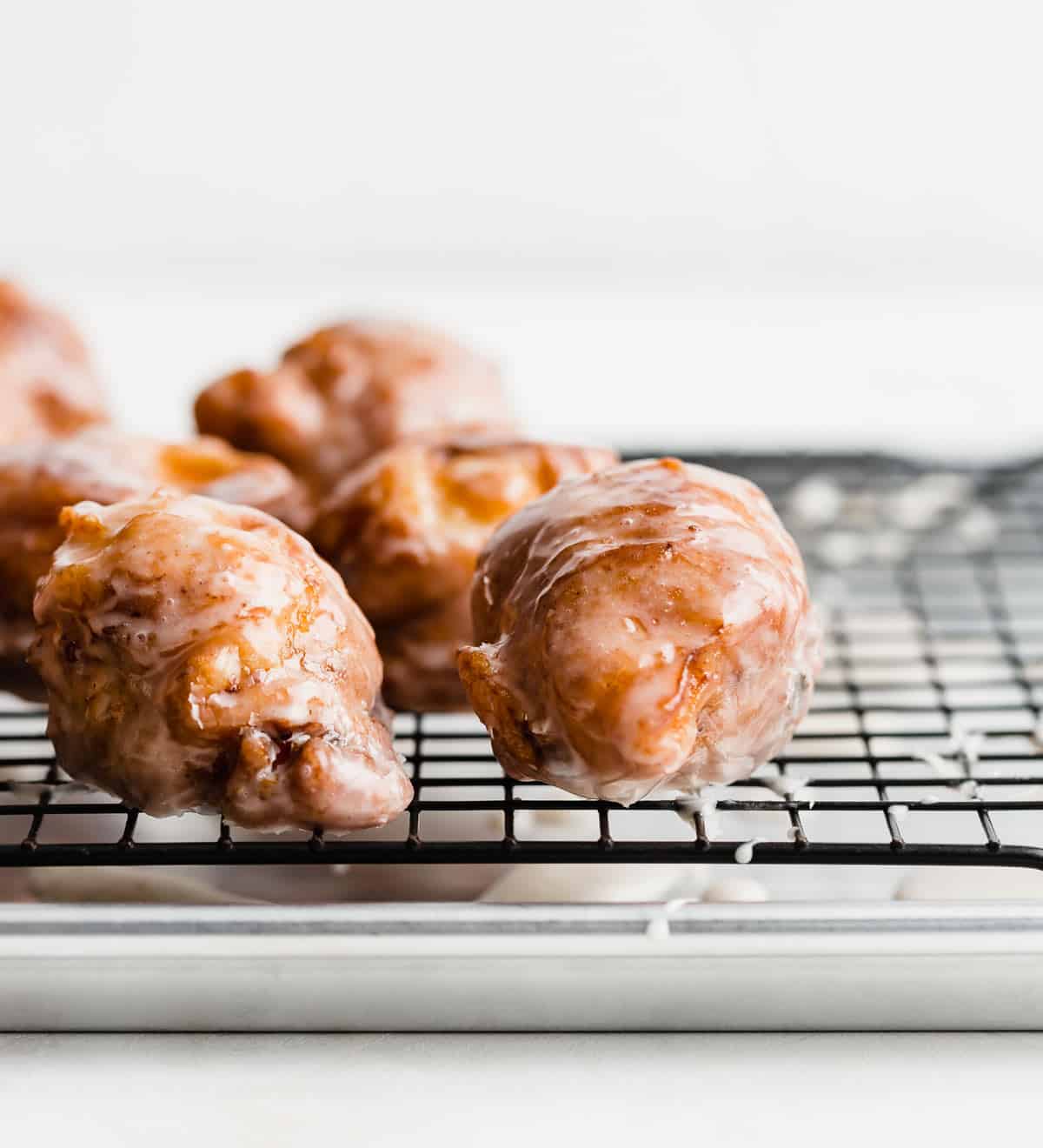 Peach Fritters topped with a glaze, on a black cooling rack.