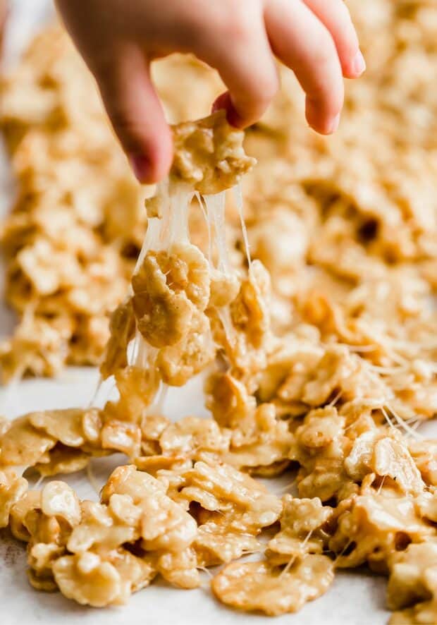 A hand pulling up a gooey piece of marshmallow coated special k cereal.
